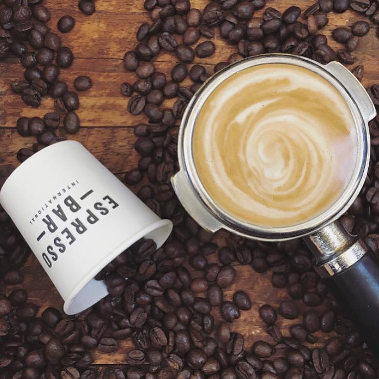 pot of coffee surrounded by spilt coffee beans